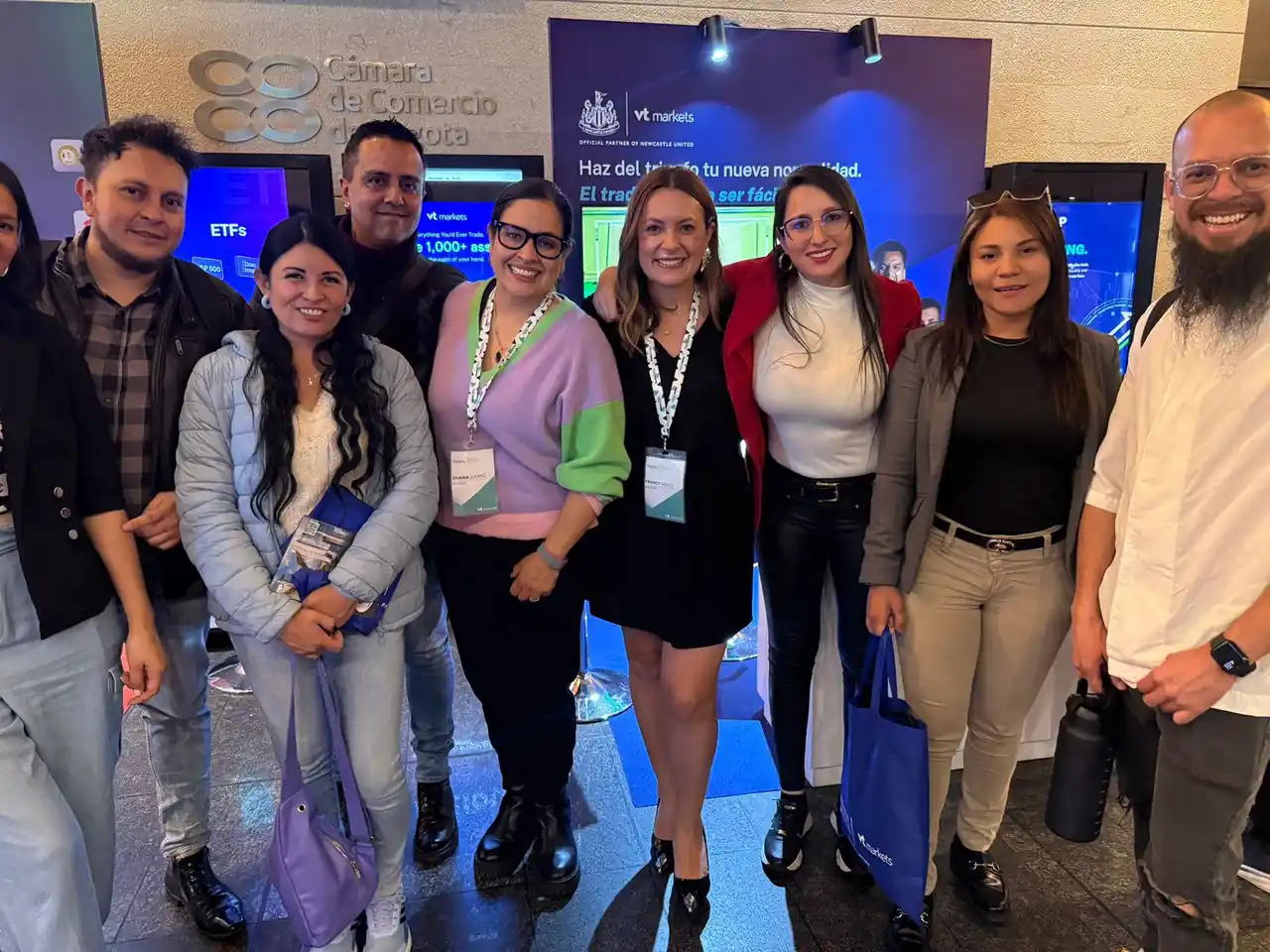 Equipo de Regla Cero en el encuentro de VT Markets celebrado en la Cámara de Comercio de Bogotá, frente al panel de patrocinio del Newcastle United.